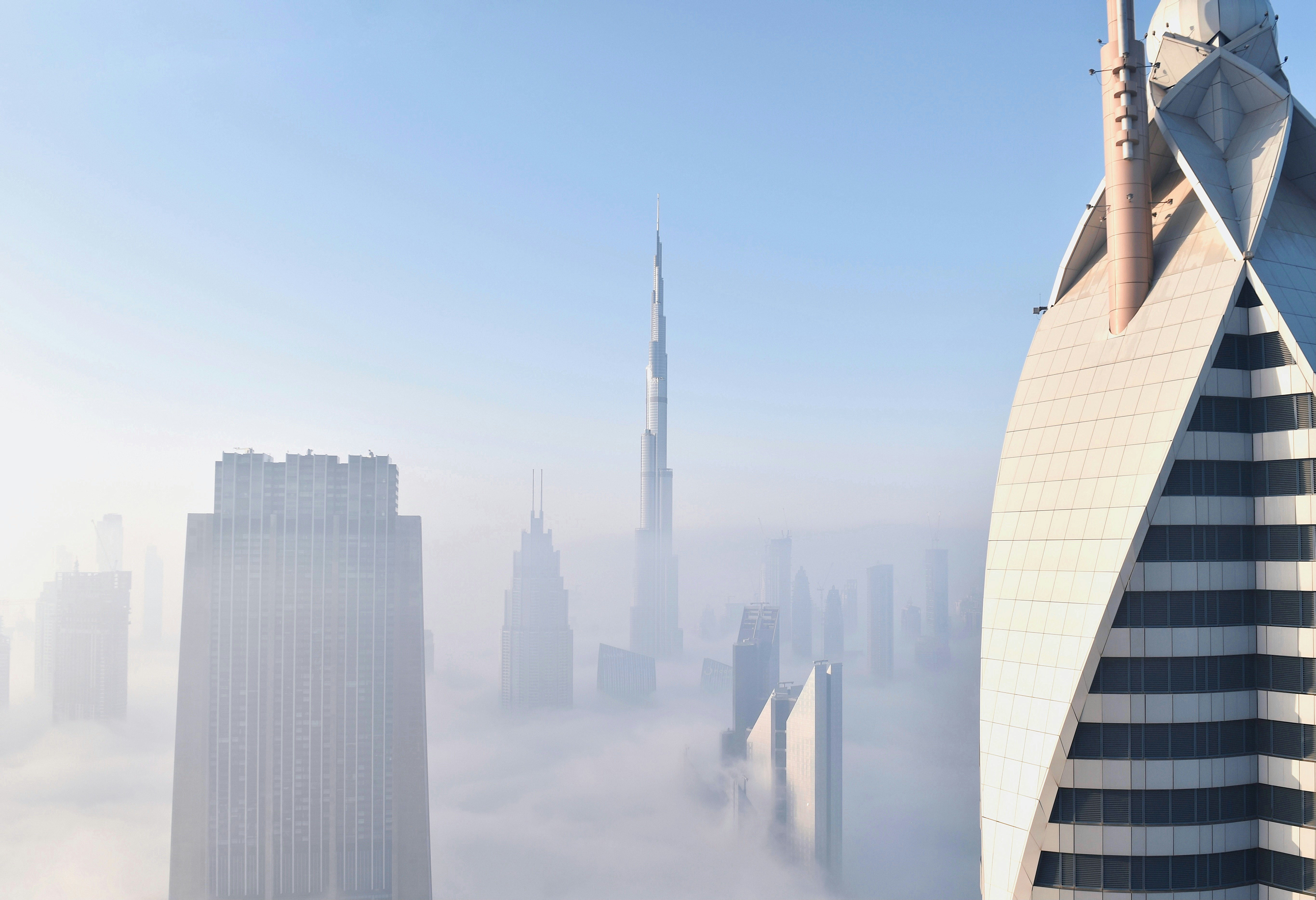 Dubai skyscrapers and the Burj Khalifa rising above thick morning fog