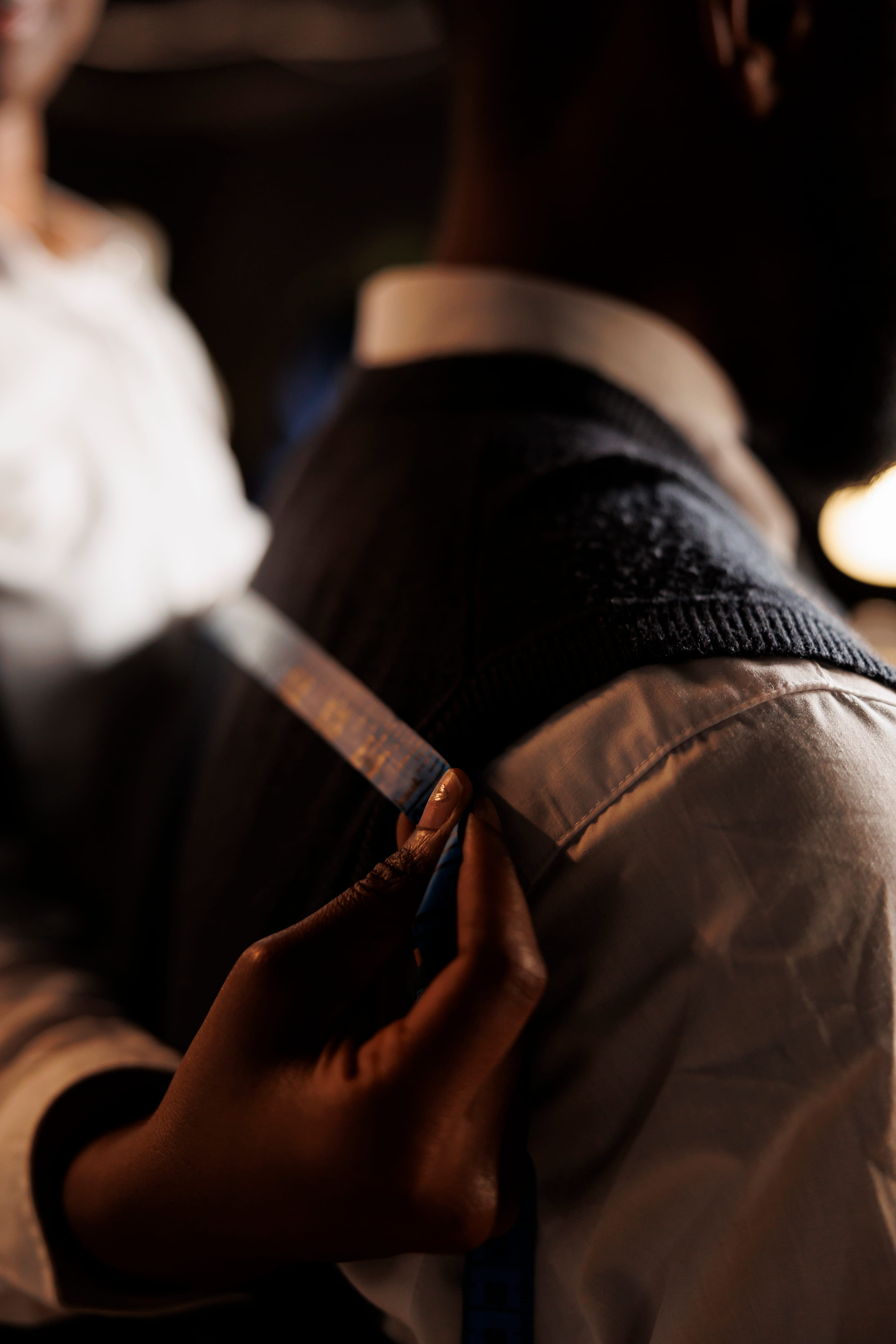 Tailor measuring a client's shoulder with a tape measure