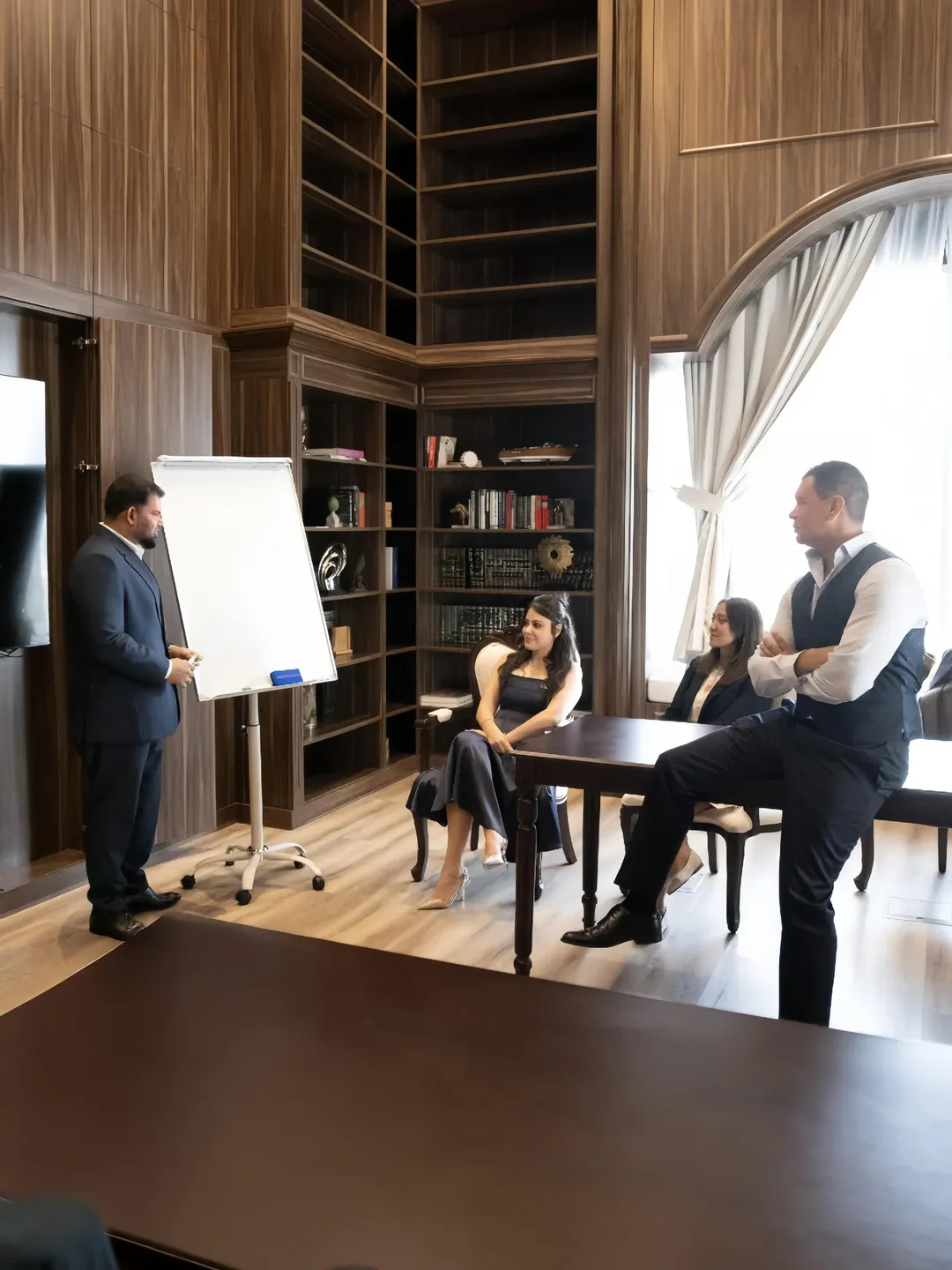 Colleague presenting at a flip chart in a wood-panelled meeting room