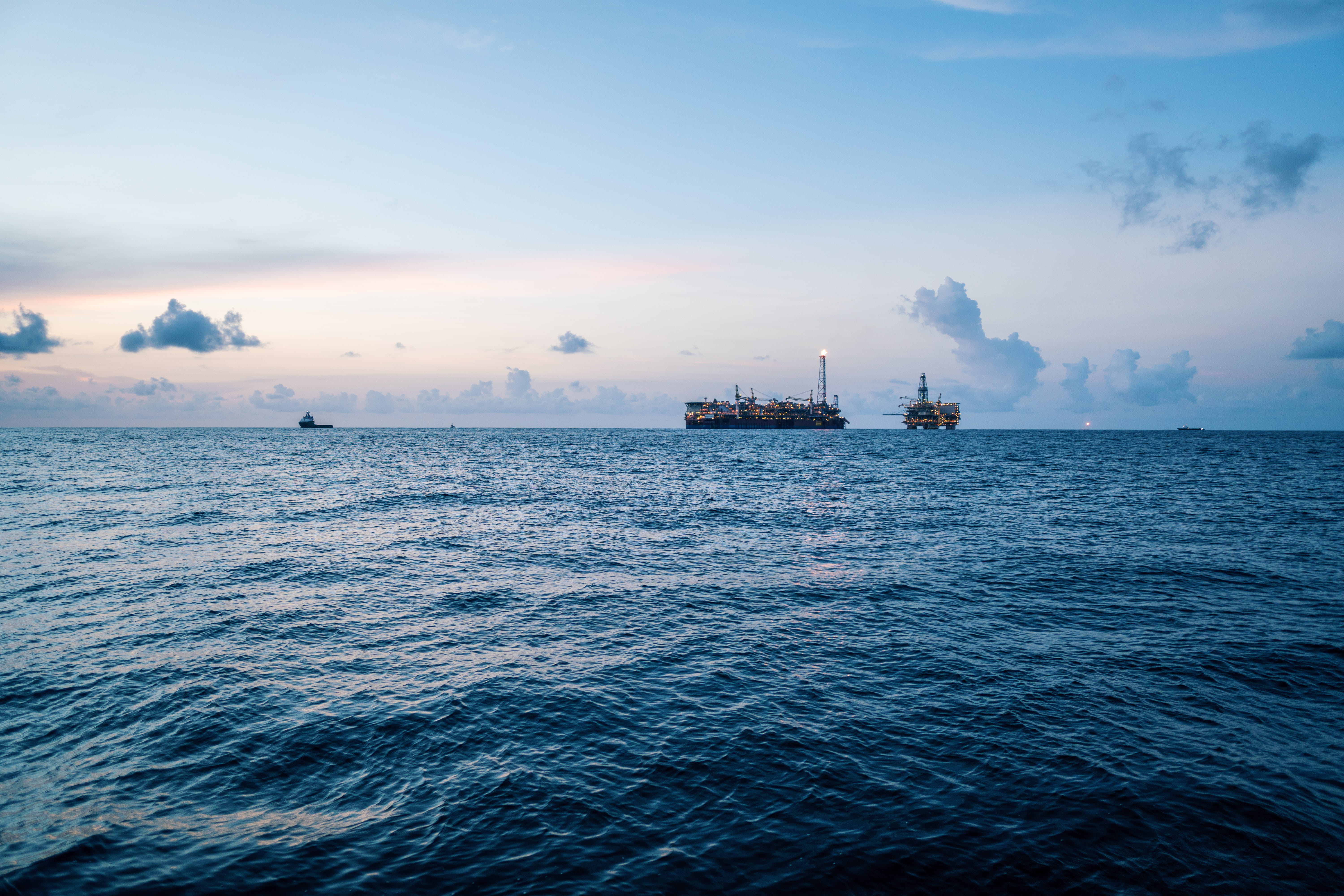 Offshore oil platform and production vessel on the horizon at dusk