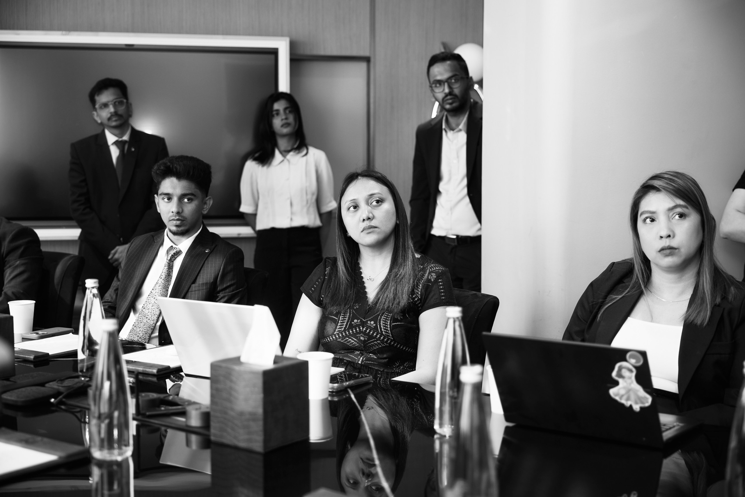 Colleagues listening intently around a boardroom table, in black and white
